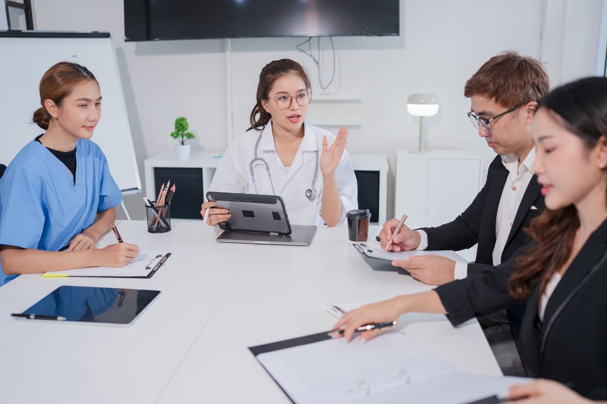 Team of Asian doctors and businesspeople are meeting in a hospital conference room.